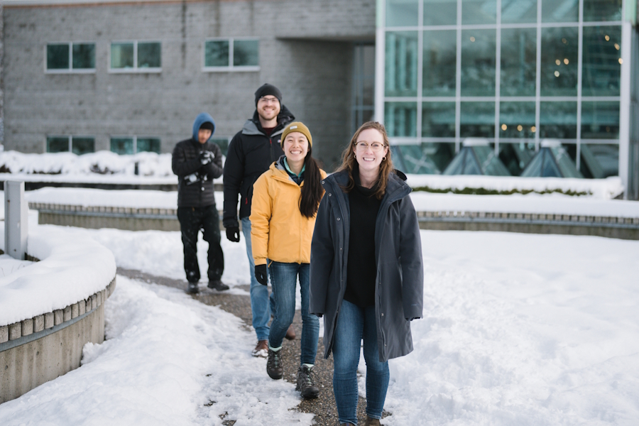 Four students walking outside Regent's building on a snowy day.
