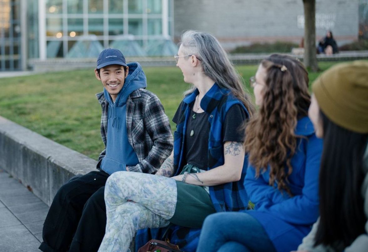 Three students sitting outside in cool weather
