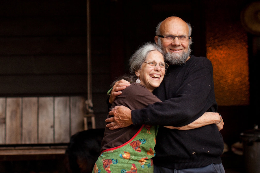 Mary Ruth and Loren Wilkinson embrace in front of a porch swing.